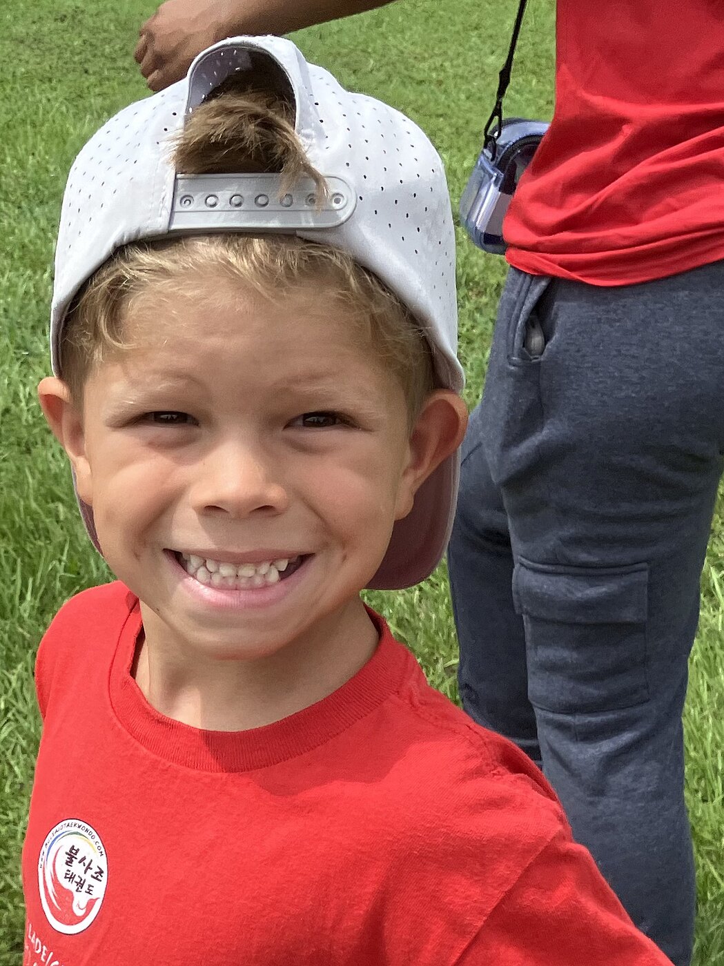 A grinning camper in a Bulsajo camp shirt and a backwards cap out on a field trip