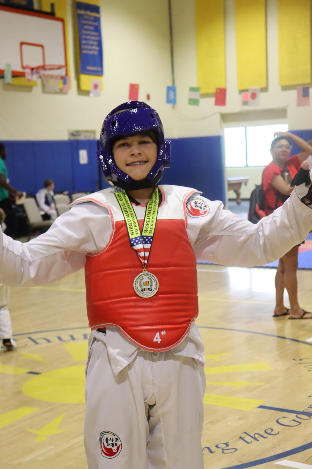 A Bulsajo student in chest protector and headgear, arms wide, wearing his medal