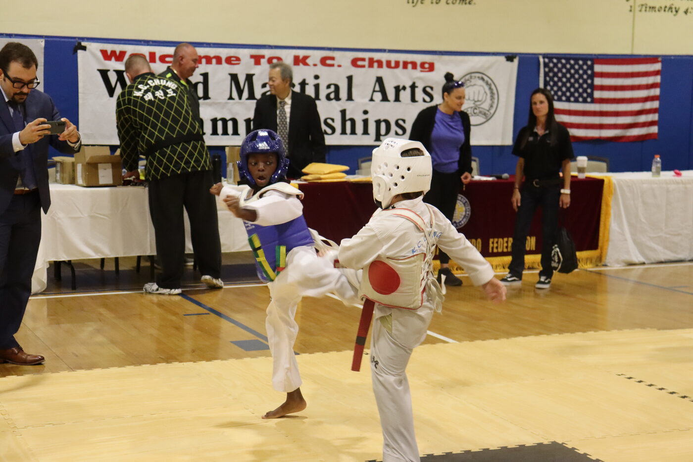 Two young Bulsajo students sparring in headgear and chest protectors under the World Martial Arts Championships banner