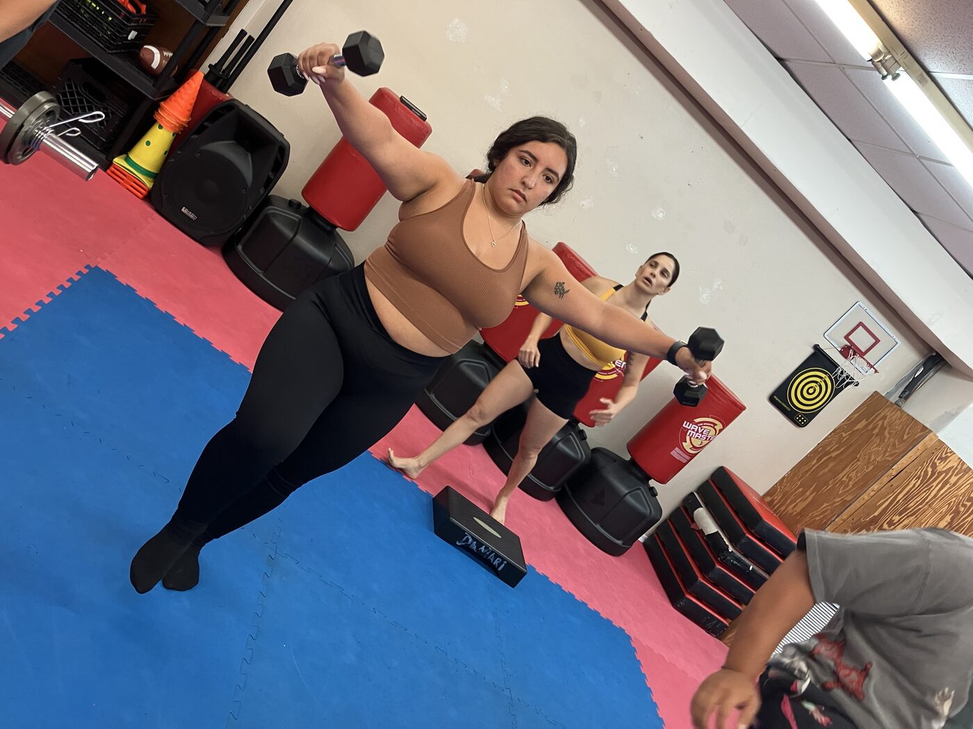 Two women training with dumbbells in the women's class at the dojang