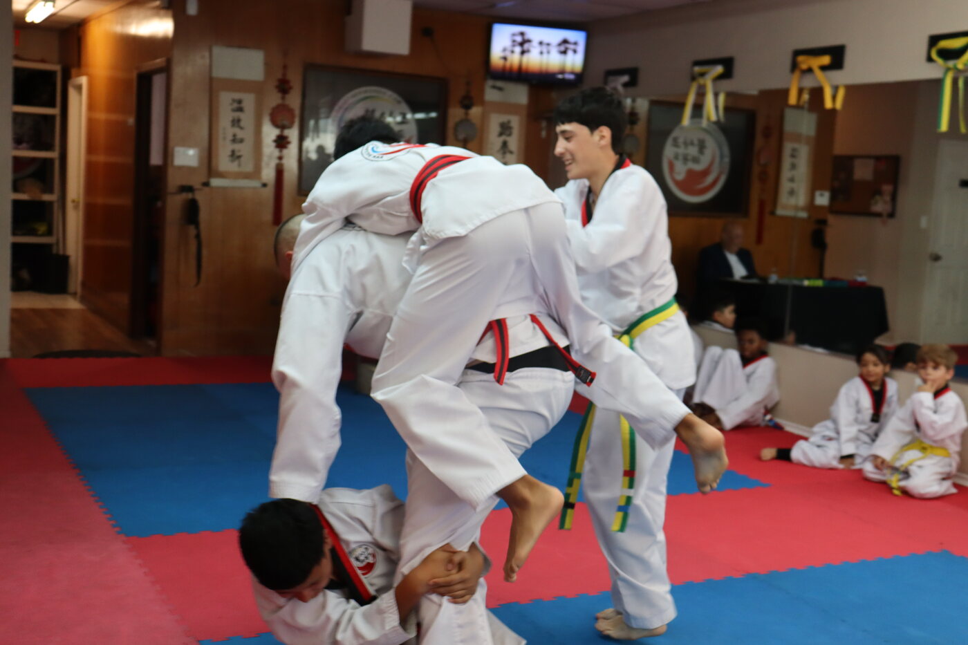 Students wrestling on the mats, one lifting his partner off the floor